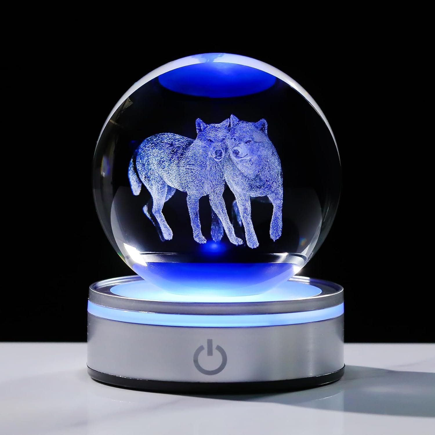 A crystal ball with two wolves etched inside, illuminated by blue light, resting on a silver base with a power button symbol.