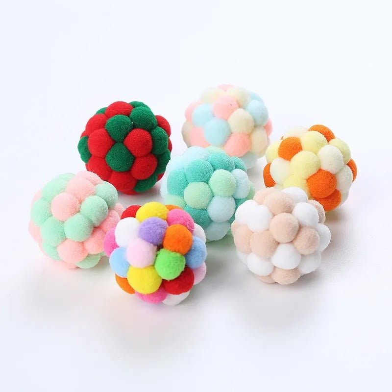 A group of colorful pom pom balls auto-drafted onto a white surface.