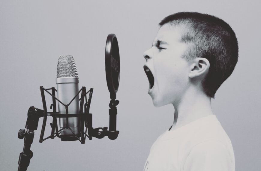 Young boy singing passionately into a studio microphone.