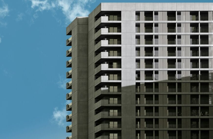 Modern high-rise apartment building against a clear blue sky with clouds.