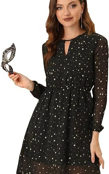 A woman in a black metallic star-patterned dress holding a masquerade mask.