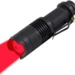 A black flashlight emitting a red light beam.