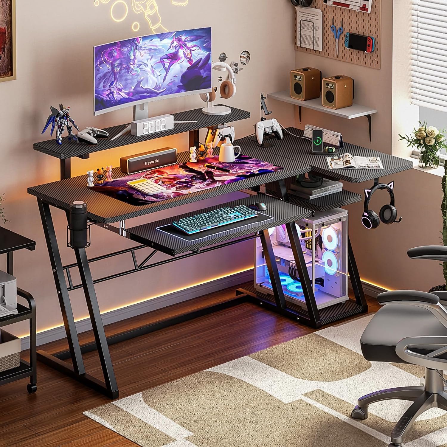 A modern gaming setup featuring a wide desk with a curved monitor, gaming peripherals, LED lighting, two shelves with decor, and a gaming PC with RGB lighting. The room has wooden flooring and a rug.