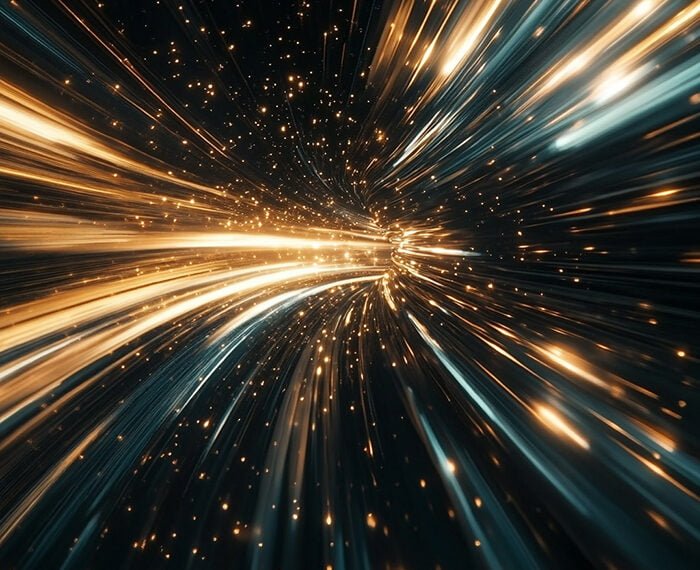 A dynamic image showing streaks of gold and blue light extending outward from a central point against a dark background, resembling the optical effects of traveling through space at high speed.