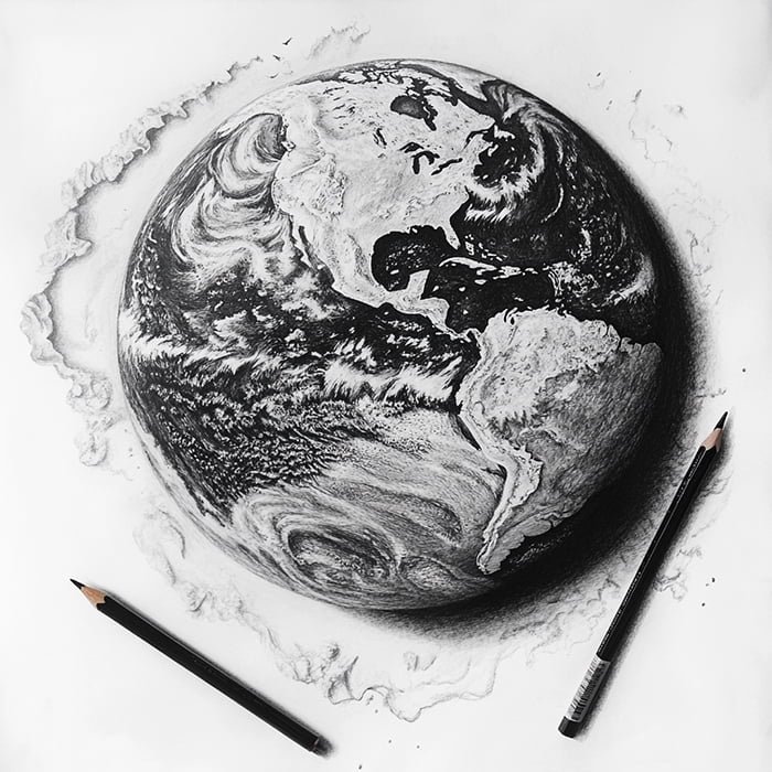 A detailed black-and-white pencil drawing of the Earth with two pencils placed diagonally at the bottom, appearing to be in the midst of creating the artwork.