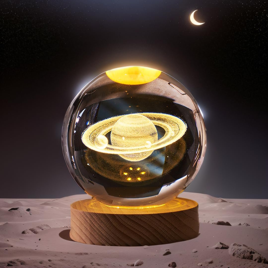 A glass sphere with a glowing Saturn inside rests on a wooden base on a lunar-like surface, beneath a crescent moon in a starry night sky.