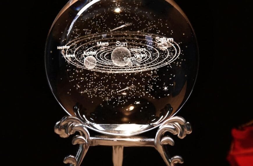 A glass orb displays a 3D solar system model, including planets Mars, Earth, Jupiter, and Saturn, with labeled orbits around the Sun; mounted on a decorative stand.