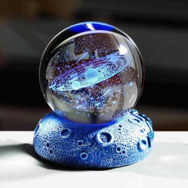 A glass orb displays a holographic model of a solar system, resting on a textured, blue, moon-like base.