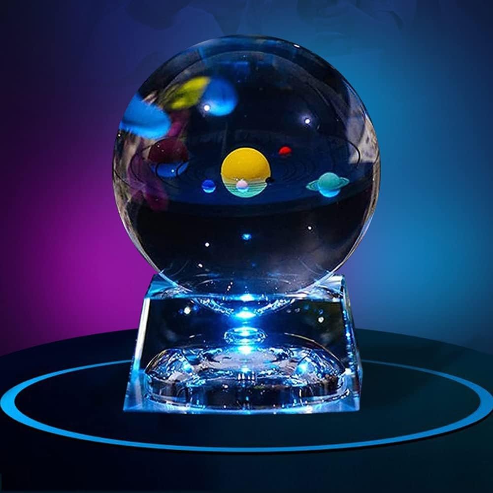 Glass orb displaying the solar system with colorful planets, set on a clear stand against a dark gradient background.