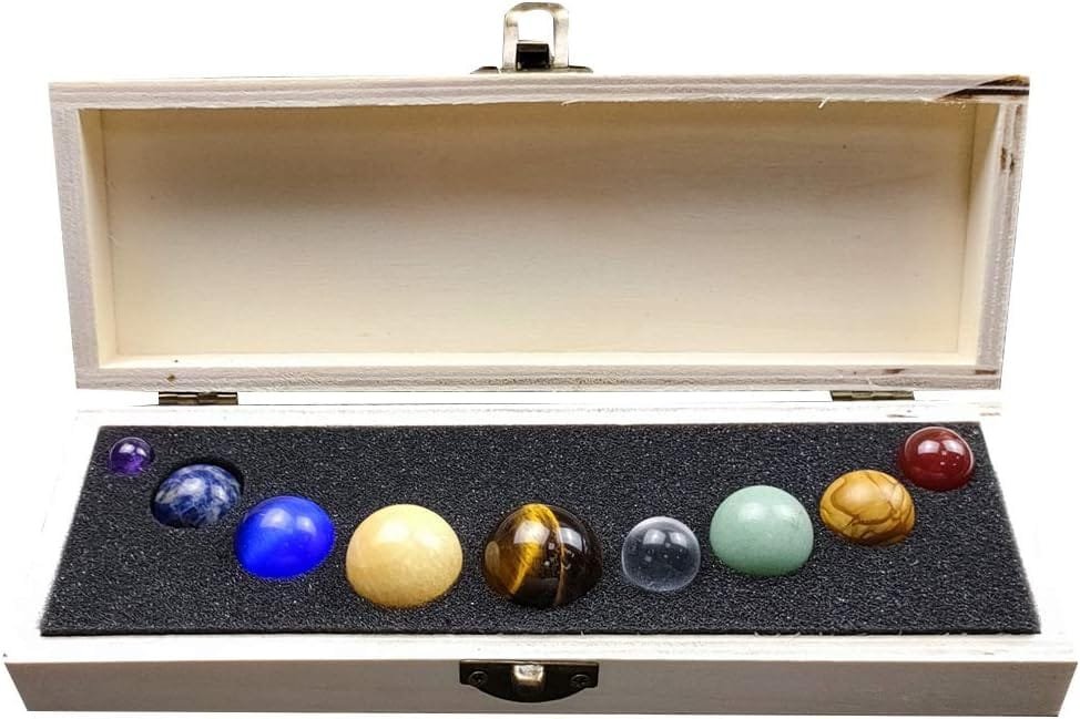 A wooden box containing nine colorful stone spheres arranged in a row on black foam.