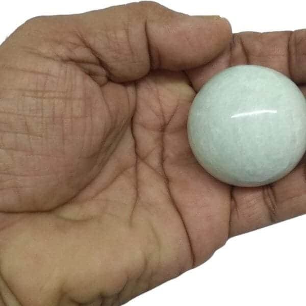 A hand holding a smooth, round white stone.