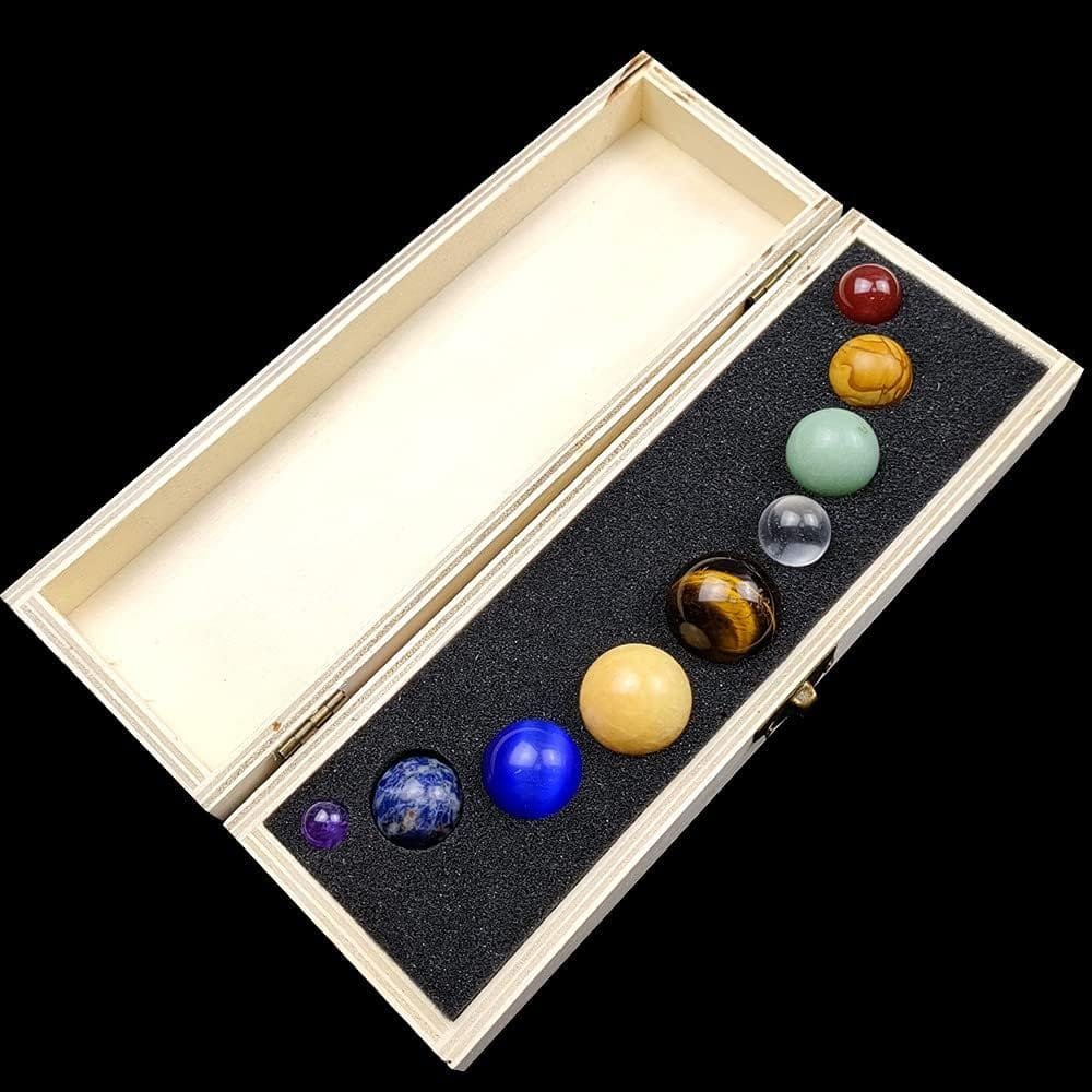 A wooden box with foam insert holds eight polished stone spheres of various colors and sizes.