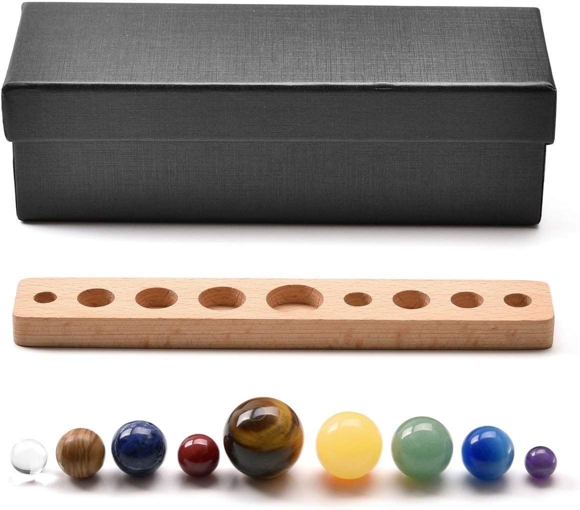 Set of colorful spheres with different sizes next to a black box and a wooden measuring board with round slots.