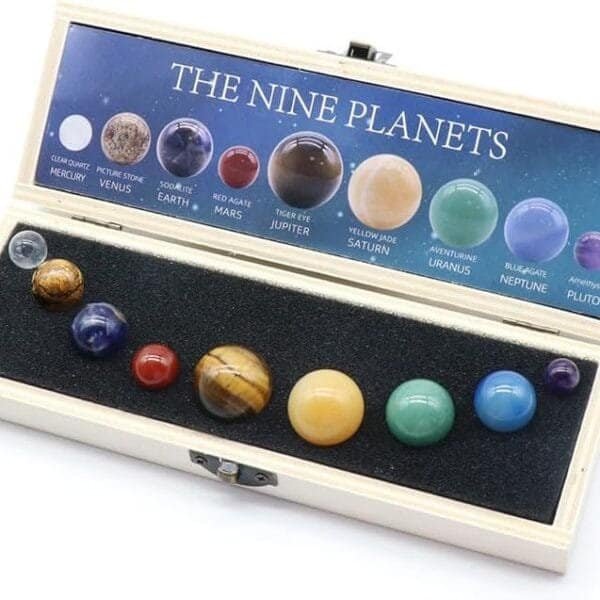 A Chakra Healing Crystal Sphere Ball by Celestial Gifts set includes nine planet-labeled spheres, symbolizing the solar system, housed in a wooden box with a foam insert.