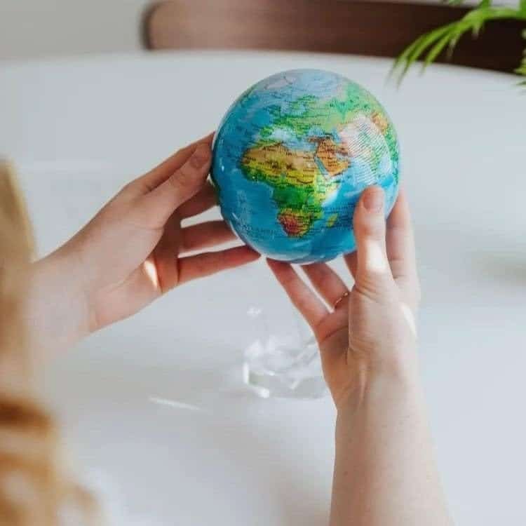 A person holds the intricately crafted Globe Relief Map Blue 6", concentrating on Africa, against a softly blurred background.