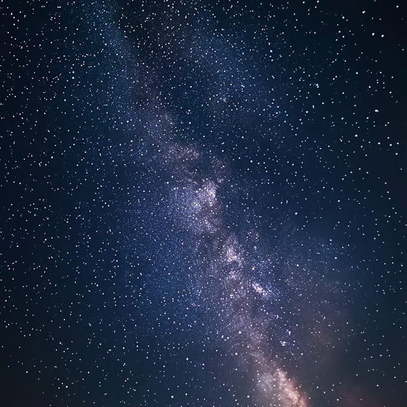 A star-filled night sky unveils the Milky Way galaxy gracefully stretching across the center.