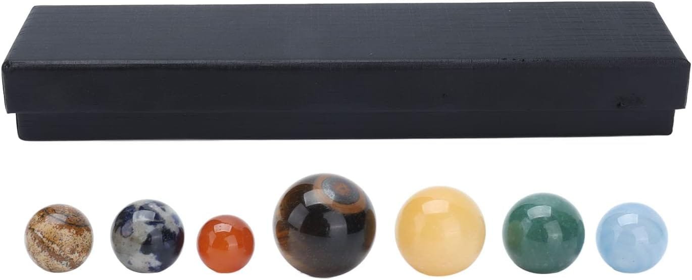 A set of six polished stone spheres in varying colors placed in front of a black rectangular box.