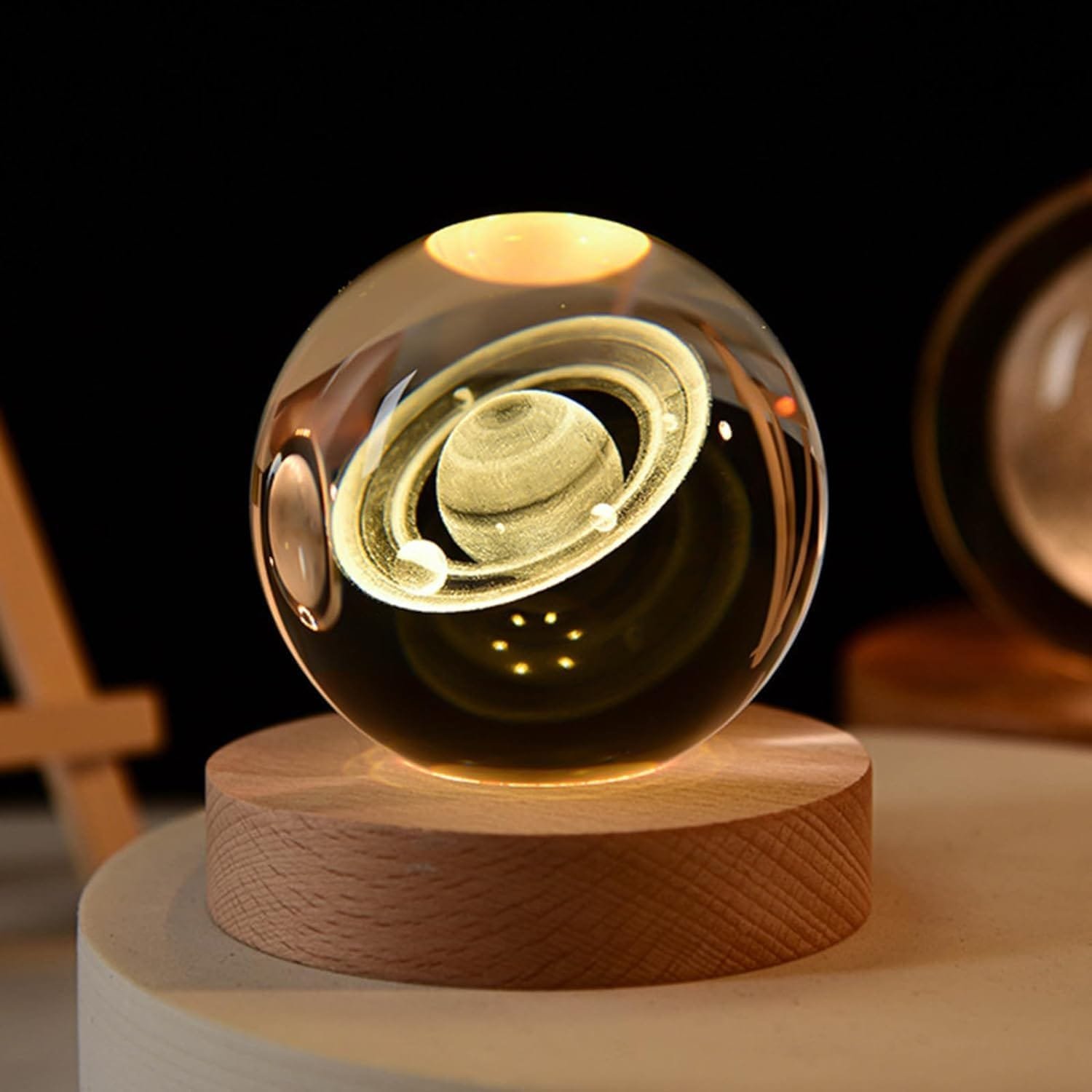 A glass orb with an etched image of Saturn sits on a wooden base.