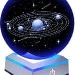 A 3D model of the solar system inside a glowing blue crystal ball on a stand, showing labeled planets and stars with a power button on the base.