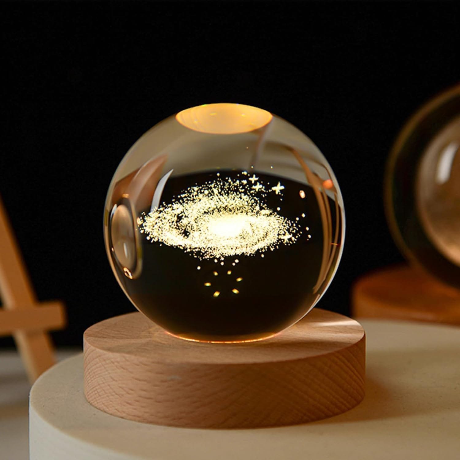 A glass orb with a glowing galaxy pattern inside, resting on a wooden stand against a dark background.