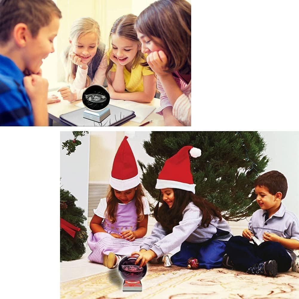 Children sitting in two separate settings, one group watching a small display and another group in Santa hats around a small appliance.