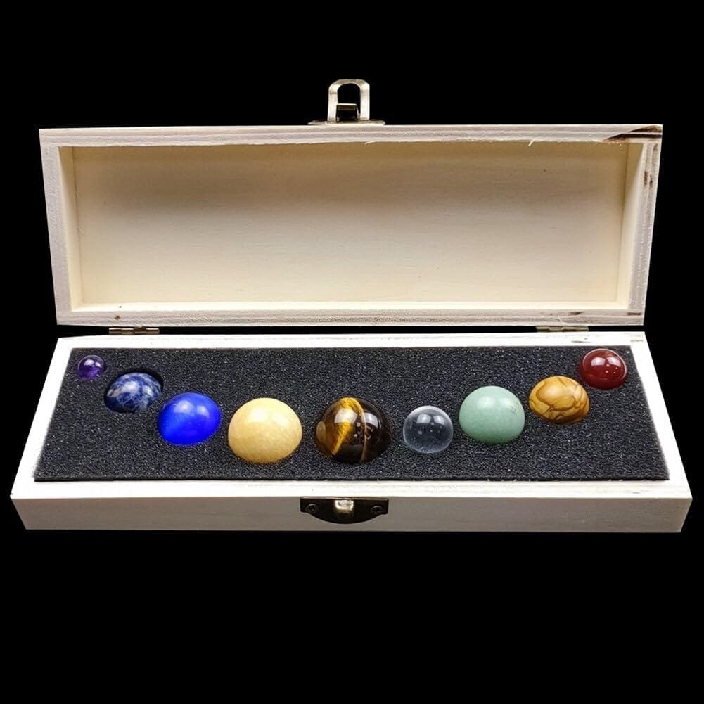 A set of nine gemstone spheres arranged in a wooden box with black foam lining.