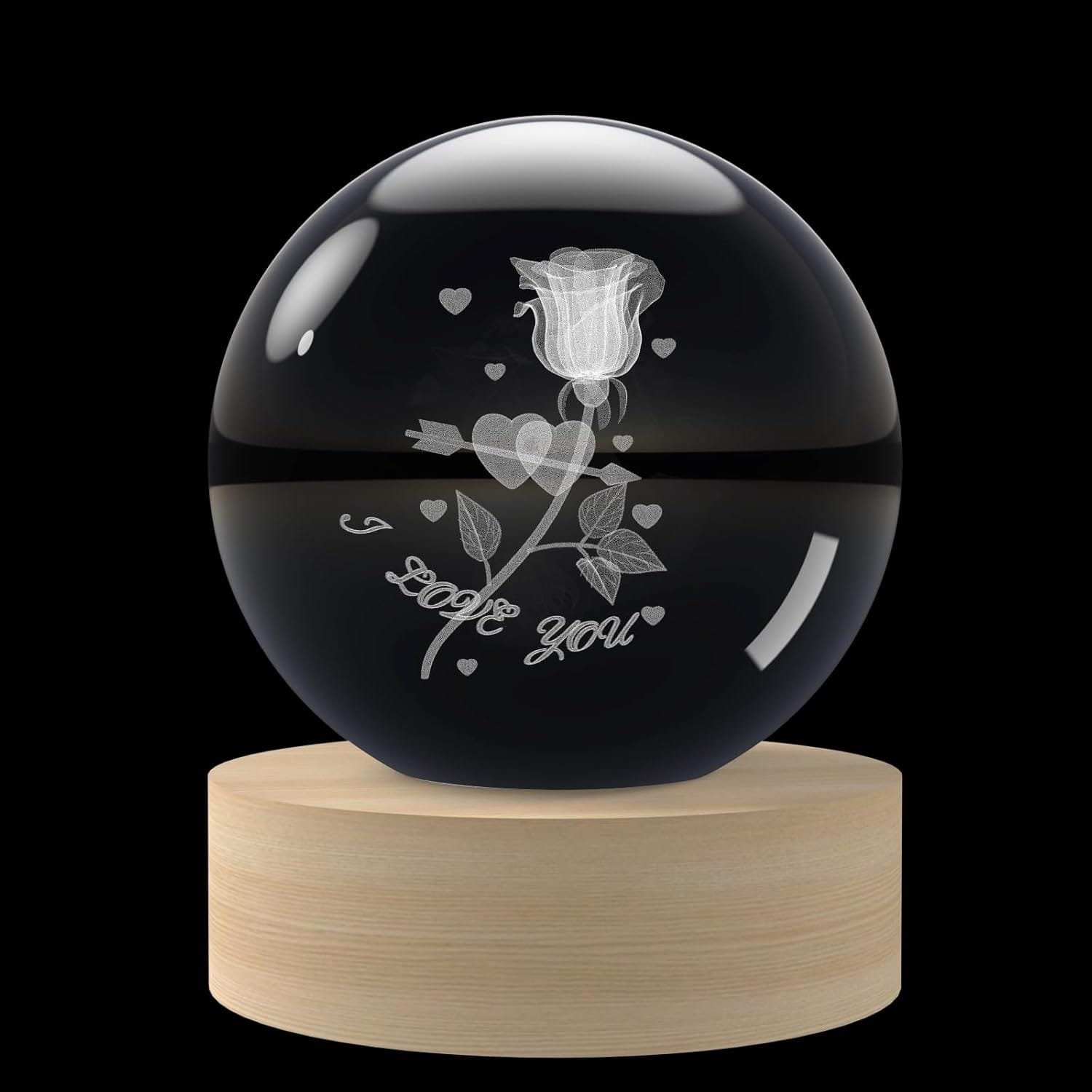 A crystal ball with a 3D rose and hearts design. The phrase "I love you" is etched inside. It's placed on a wooden base against a black background.