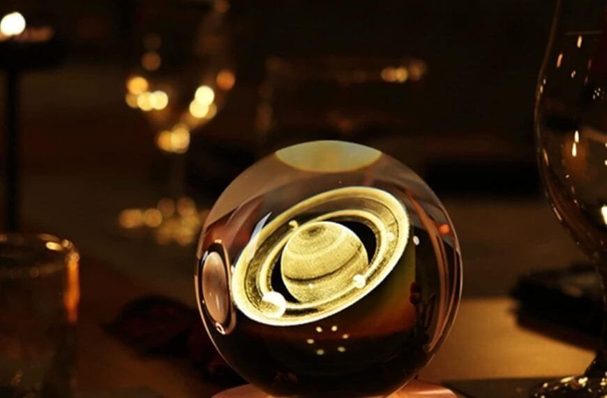 A glowing crystal ball with an image of Saturn sits on a wooden base, surrounded by dimly lit glassware.