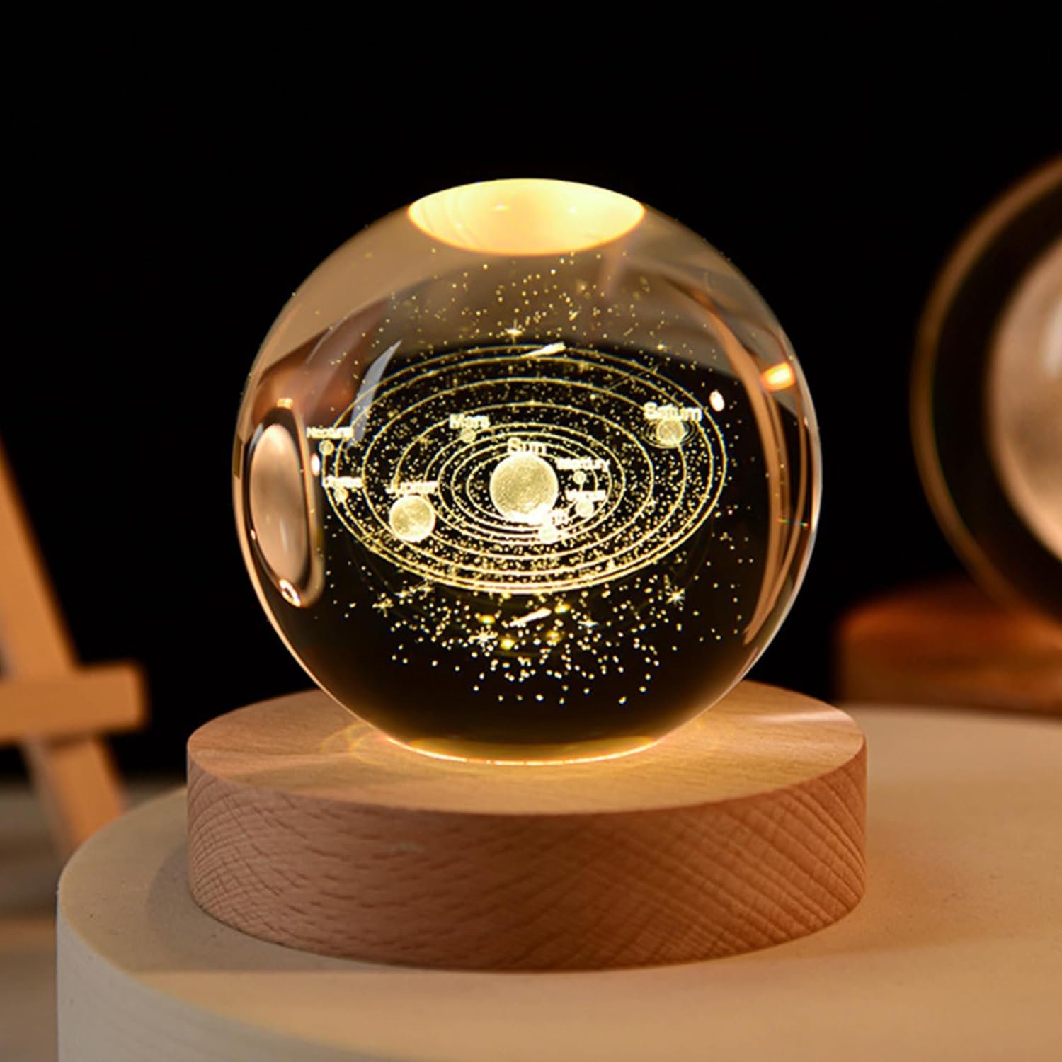 A glass orb displays a glowing model of a solar system, resting on a wooden base against a dark background.