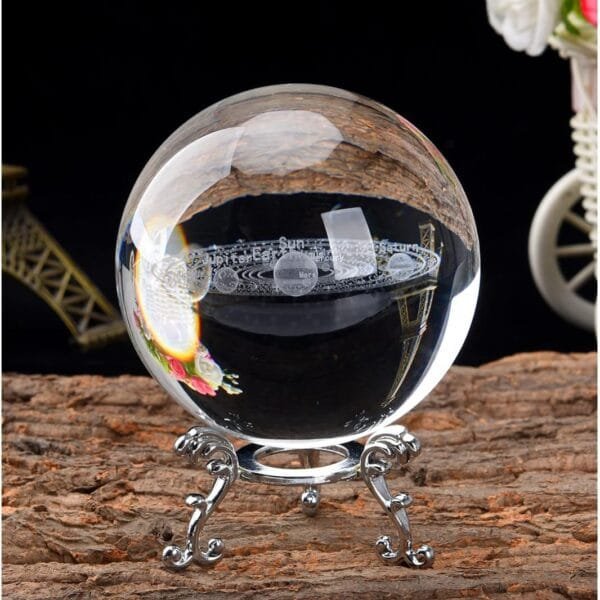 A clear crystal ball on a decorative metal stand sits on a textured wooden surface.