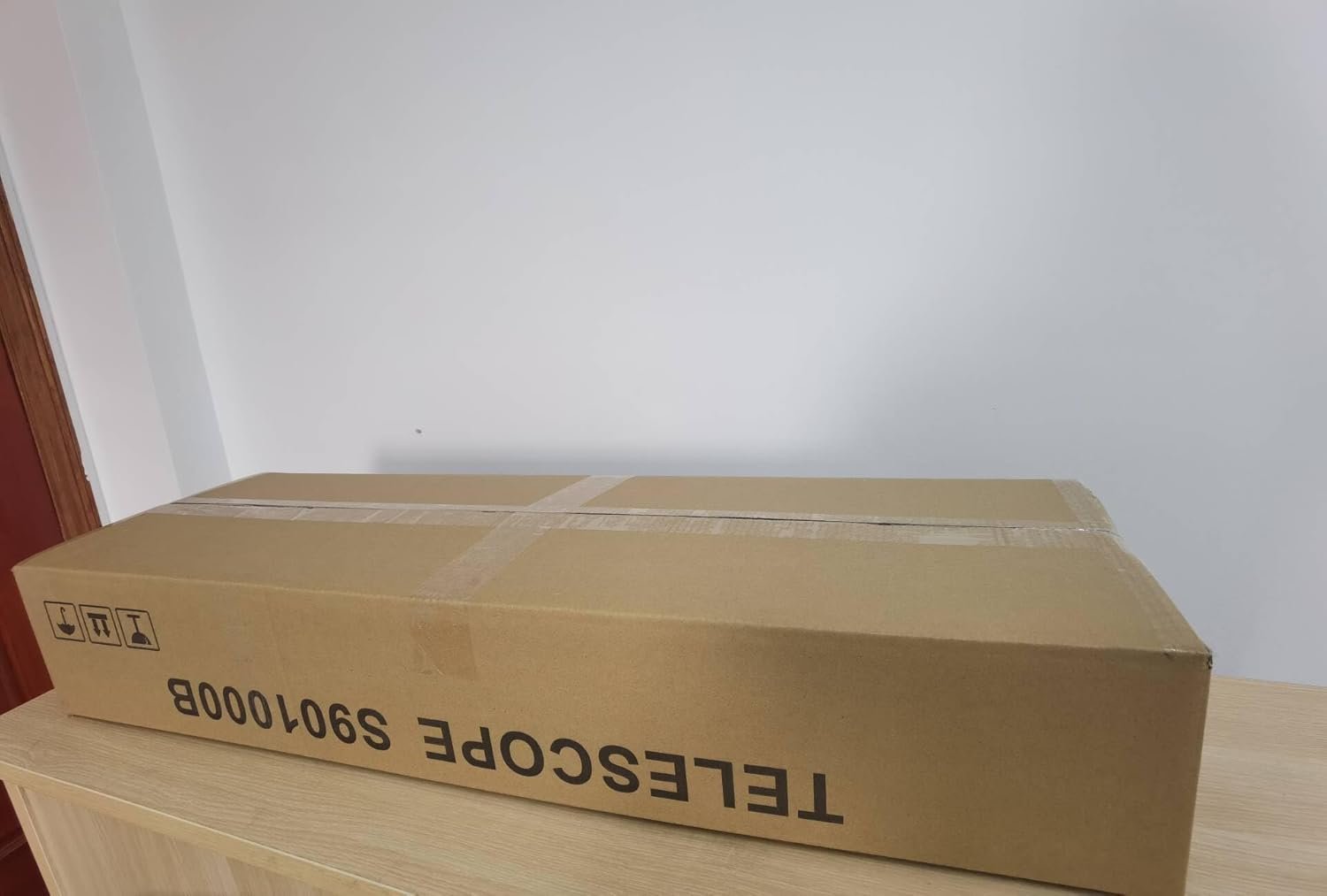 Cardboard box labeled "TELESCOPE 901000B" placed on a wooden surface.