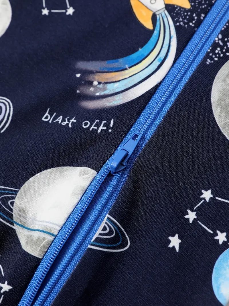 Close-up of a blue zipper on fabric with a space-themed pattern, featuring planets, constellations, a rocket, and the words "blast off!".