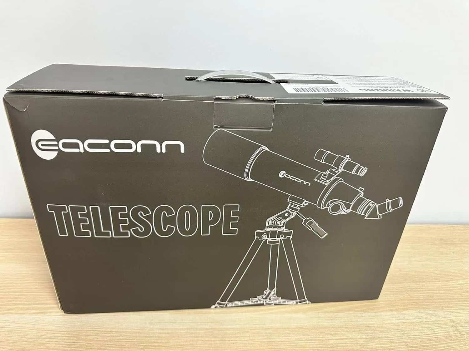 Black packaging box of an Eaconn telescope featuring a white outline illustration of the telescope on a tripod.