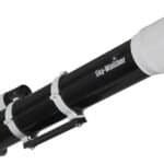 A black and white Sky-Watcher refractor telescope with an attached finderscope and eyepiece, viewed from an angled side perspective.
