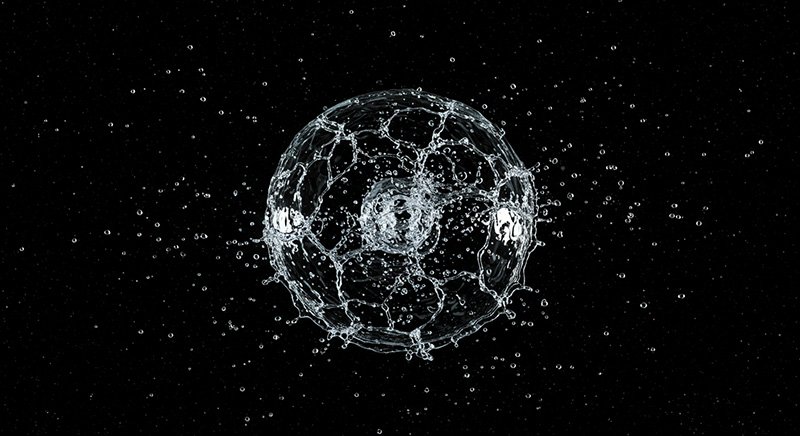 If you poured water into space, would it freeze or evaporate first? 1 A sphere of water droplets is suspended in mid-air against a black background, with smaller droplets radiating outward.