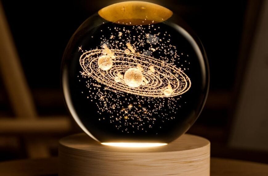 Glass sphere on a wooden base featuring a golden, illuminated model of a solar system or galaxy suspended inside the sphere.