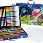 Crayola Inspiration Art Case with 140 assorted art supplies including markers, colored pencils, crayons, and paper sheets, displayed in an open carrying case with a space-themed design.