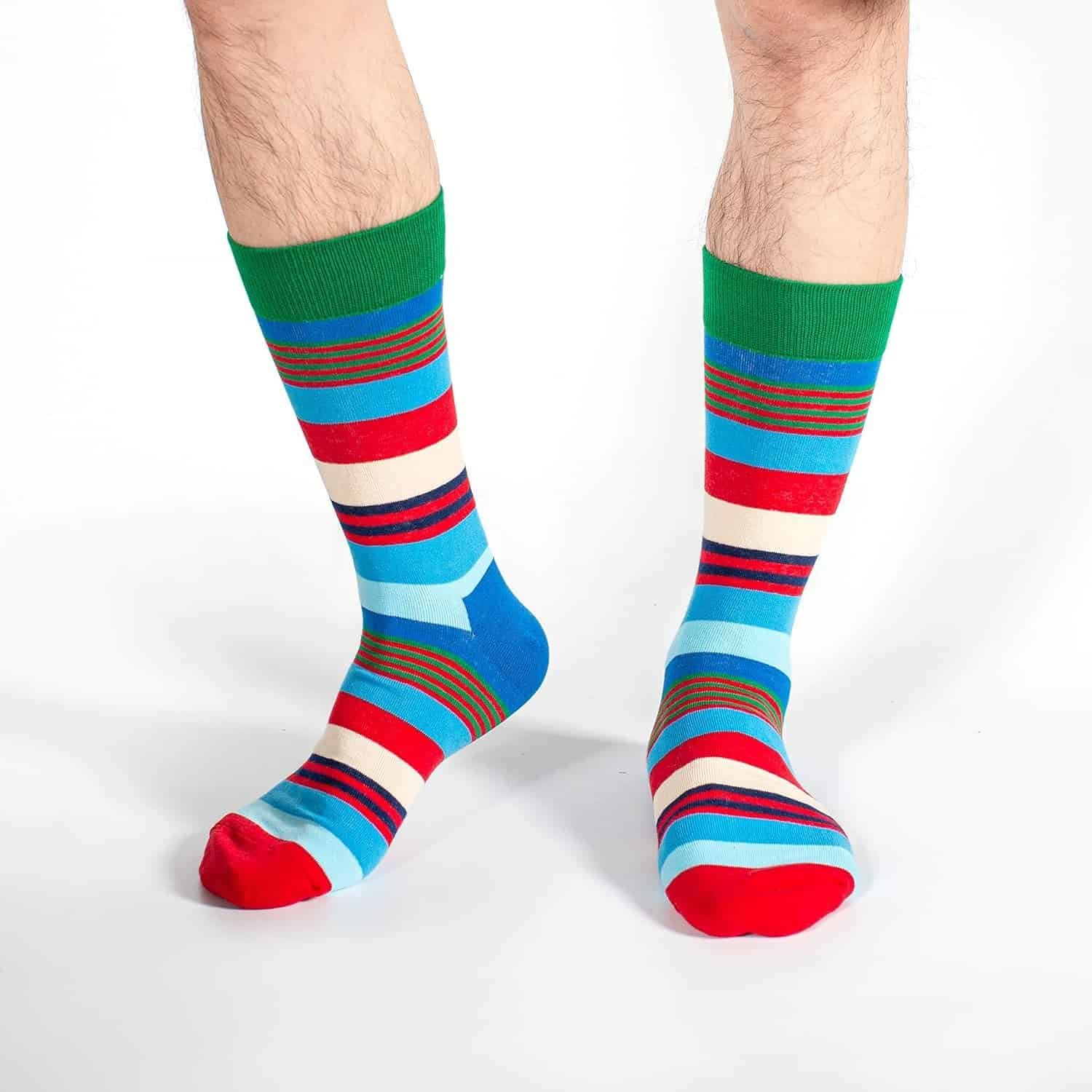 Person wearing colorful striped socks with red, blue, green, and white patterns standing on a white background. Only the lower legs and feet are visible.