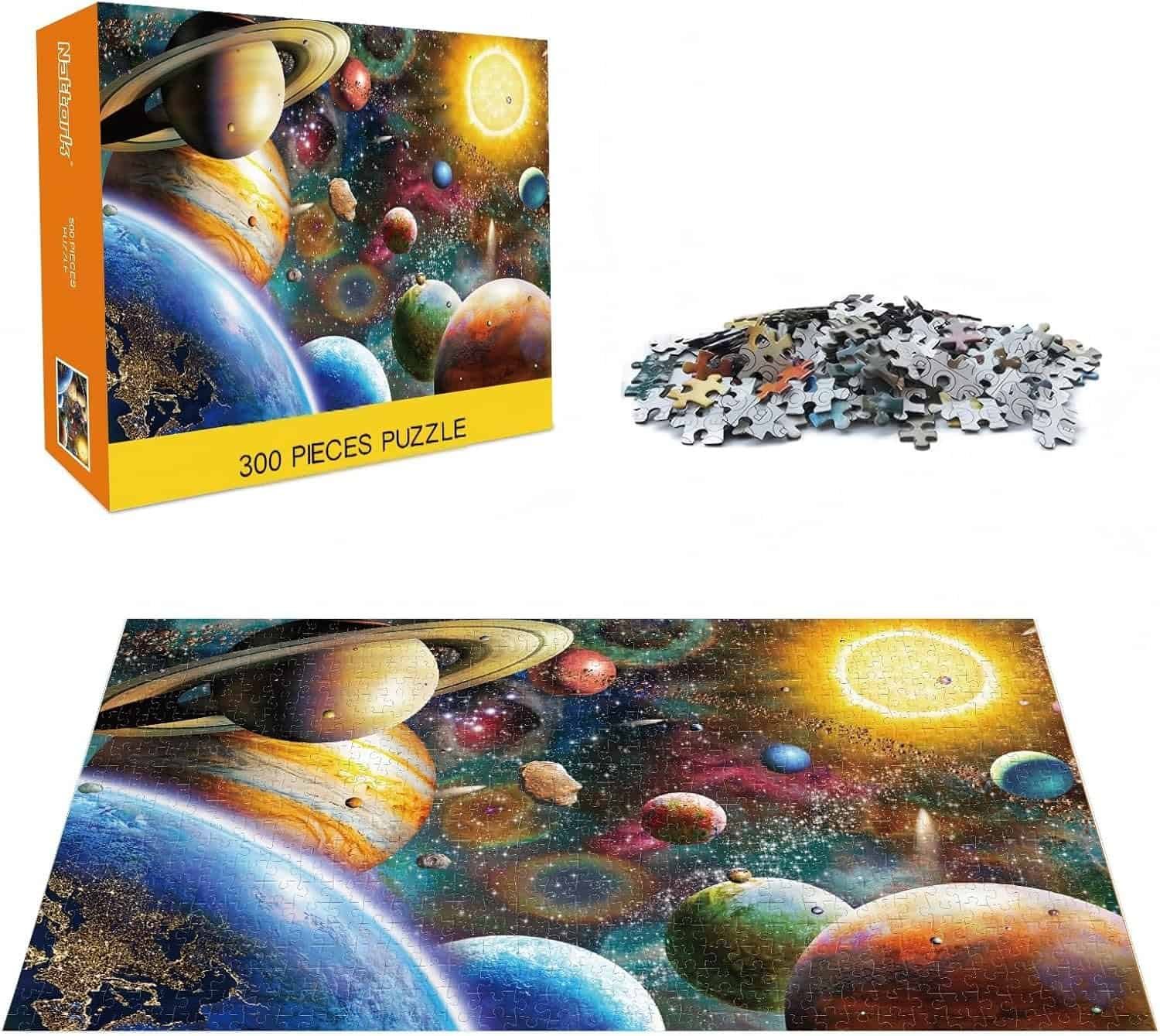 A 300-piece puzzle with its box, loose pieces, and the completed image showing a colorful outer space scene with planets and stars.
