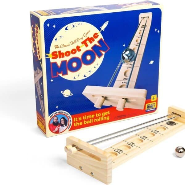 A wooden tabletop game called "Shoot the Moon" with a ball rolling device is placed in front of its colorful packaging showing the game's name and illustration of the moon and stars.