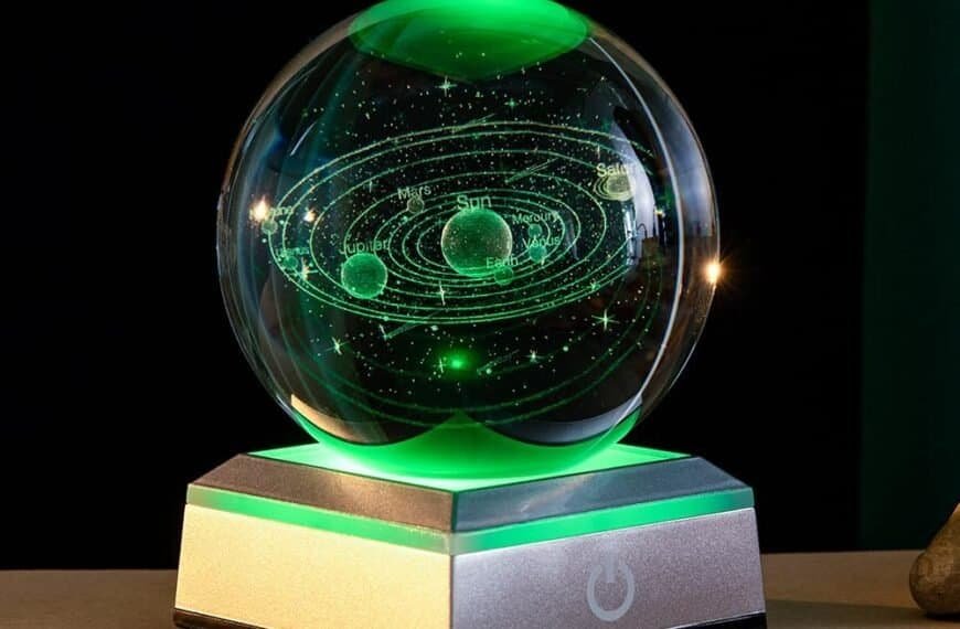 A glass orb with a laser-etched model of the solar system sits on a lit metallic base, glowing with green light.