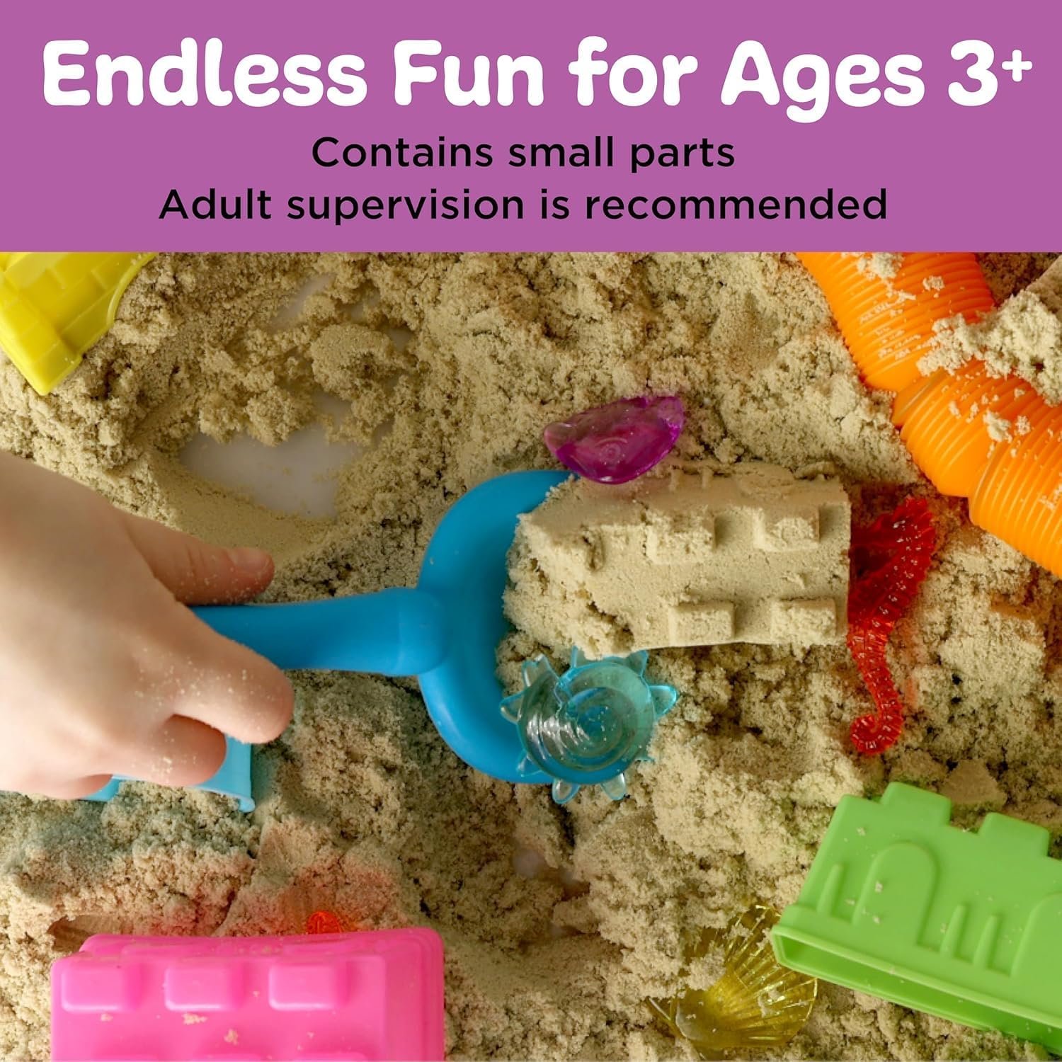 Child's hand playing with kinetic sand, plastic shovel, and colorful sand molds. Text above reads: "Endless Fun for Ages 3+. Contains small parts. Adult supervision is recommended.