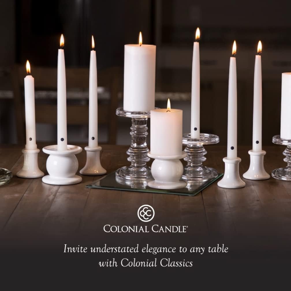 Several lit white candles of varying heights are arranged on clear glass and white holders atop a wooden table, with the Colonial Candle logo and slogan beneath.