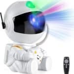 A small astronaut-shaped projector emits colorful light patterns from its helmet; a remote control is placed beside it.
