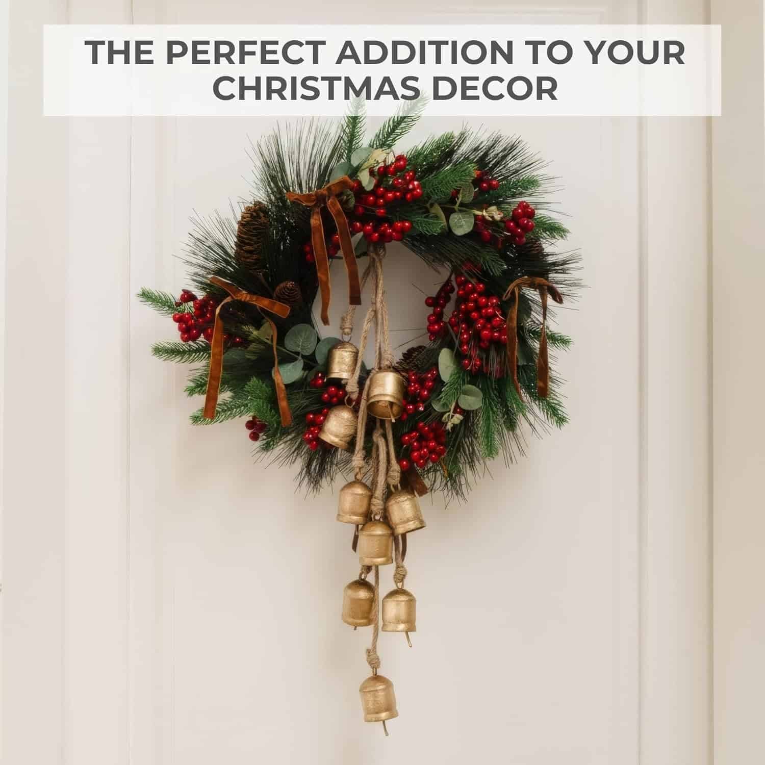 A Christmas wreath with pine branches, red berries, ribbon, and hanging gold bells is displayed on a white door. Text above reads: "The perfect addition to your Christmas decor.