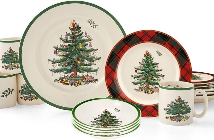 A dinnerware set with plates, bowls, and mugs featuring a Christmas tree design and some red plaid accents on select pieces.