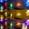 String lights featuring astronaut, rocket, and planet shapes in multiple colors, shown lit in different lighting modes; a hand is holding a remote control in the bottom image.