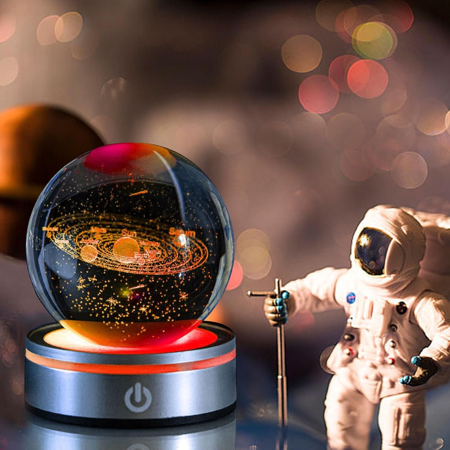 A glass orb displaying a solar system model sits on a lit base, with a toy astronaut figure standing beside it holding a staff.