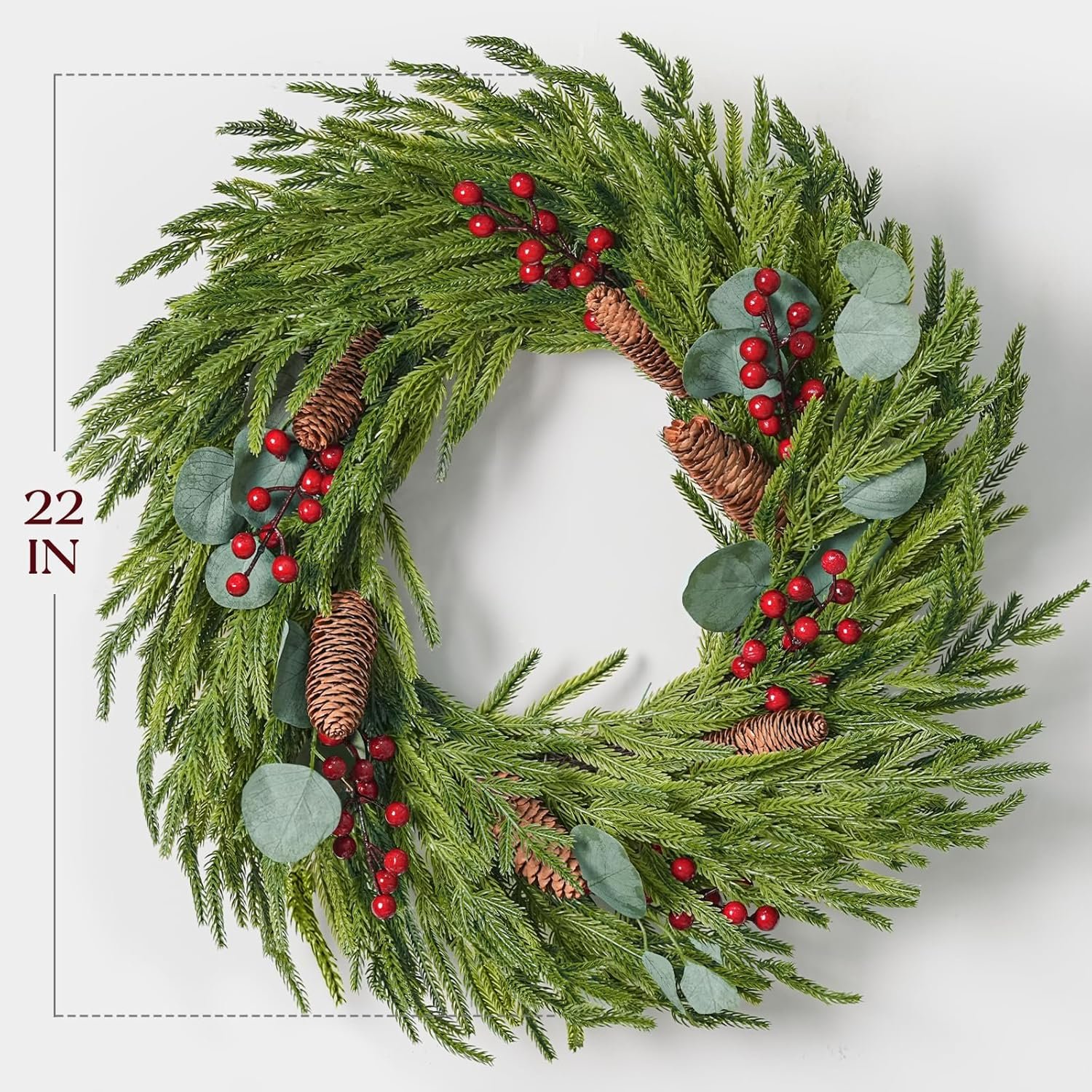 A 22-inch round wreath made of green foliage, pinecones, red berries, and eucalyptus leaves arranged in a festive style.