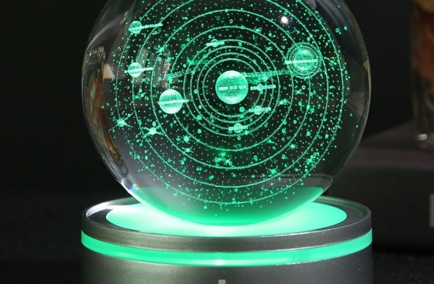 A glass sphere with a glowing green solar system model sits on a metallic base with a prominent power symbol on the front.